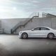 a white 2023 mercedes-amg s 63 e performance sedan seen from the drivers side in silhouette, parked on the roof of a concrete parking structure against a gray wall
